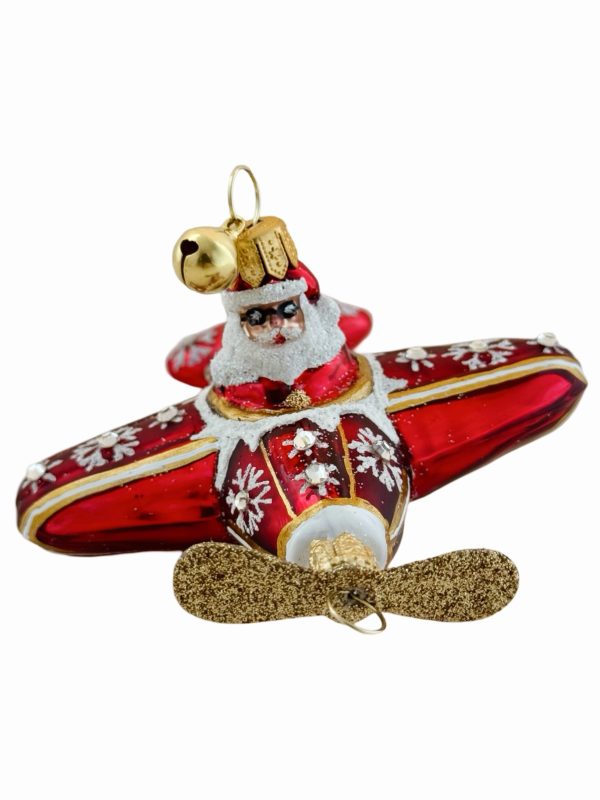 Festive Santa airplane Christmas ornament – a red and gold hand blown glass Christmas tree decoration featuring Santa Claus piloting a glittery holiday propeller plane adorned with snowflakes and snowy sparkling accents.